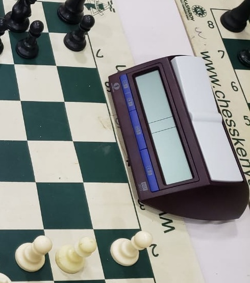 Digital chess clock beside a tournament board